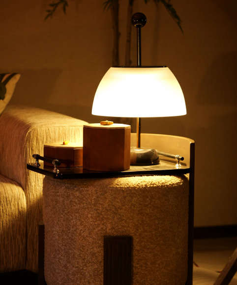 A lit lamp and lacquered boxes on a side table in the lounge